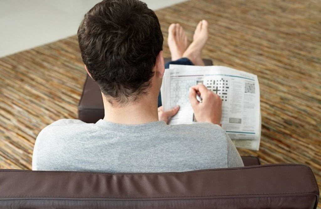 Man doing a crossword in the newspaper.