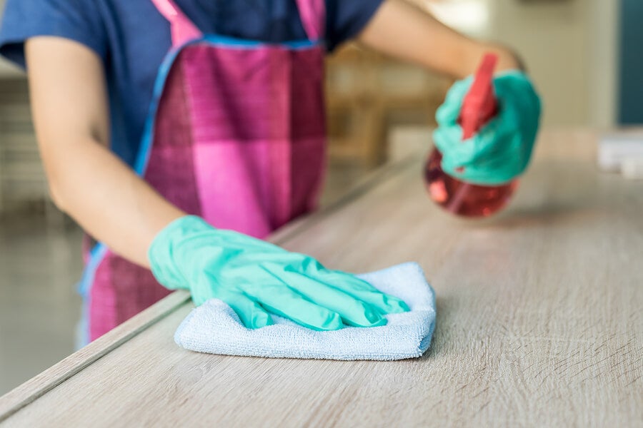 Cleaning a wooden furniture with a spray and a cloth