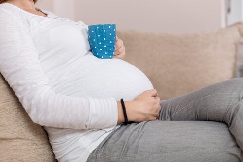 Pregnant woman sitting with cup on tummy 